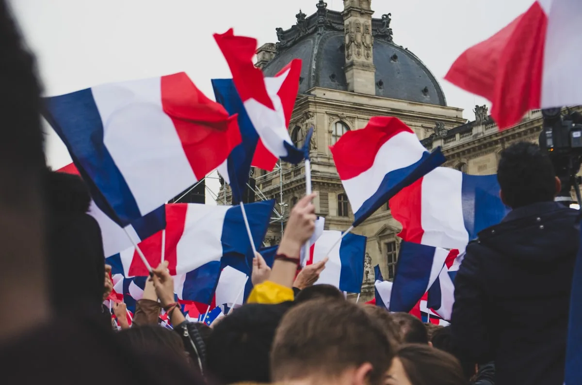 People waving the French tricolour flag in front of the Louvre in Paris